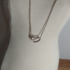 Silver tone chain necklace with open small heart pendant.